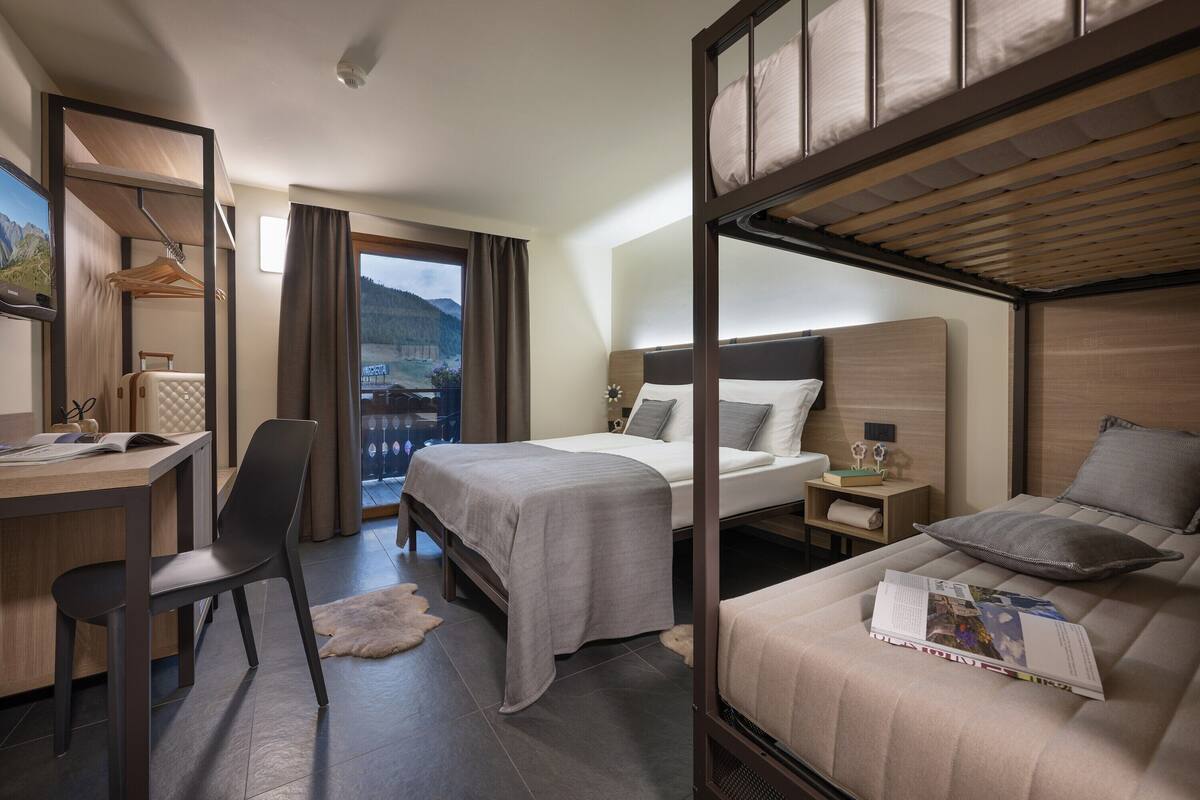 A hotel room with two beds, a desk, and a chair.