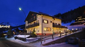 A two-story hotel with a balcony, a snow-covered driveway, and a mountain backdrop. - Hotel Loredana (Livigno)