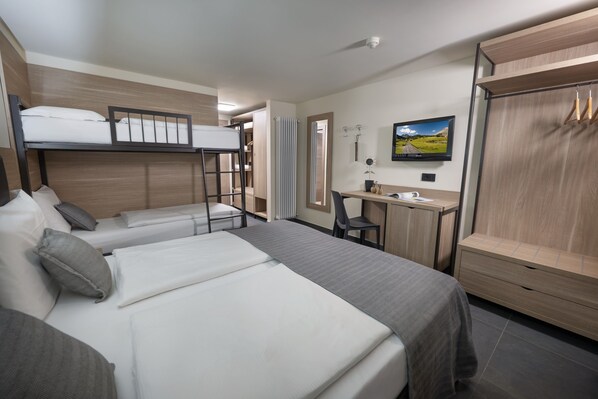 Una habitación de hotel con dos camas, un escritorio, un televisor y un armario.