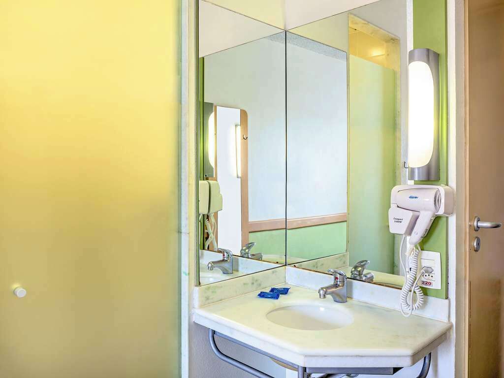 A bathroom with a sink, mirror, and a hairdryer mounted on the wall.