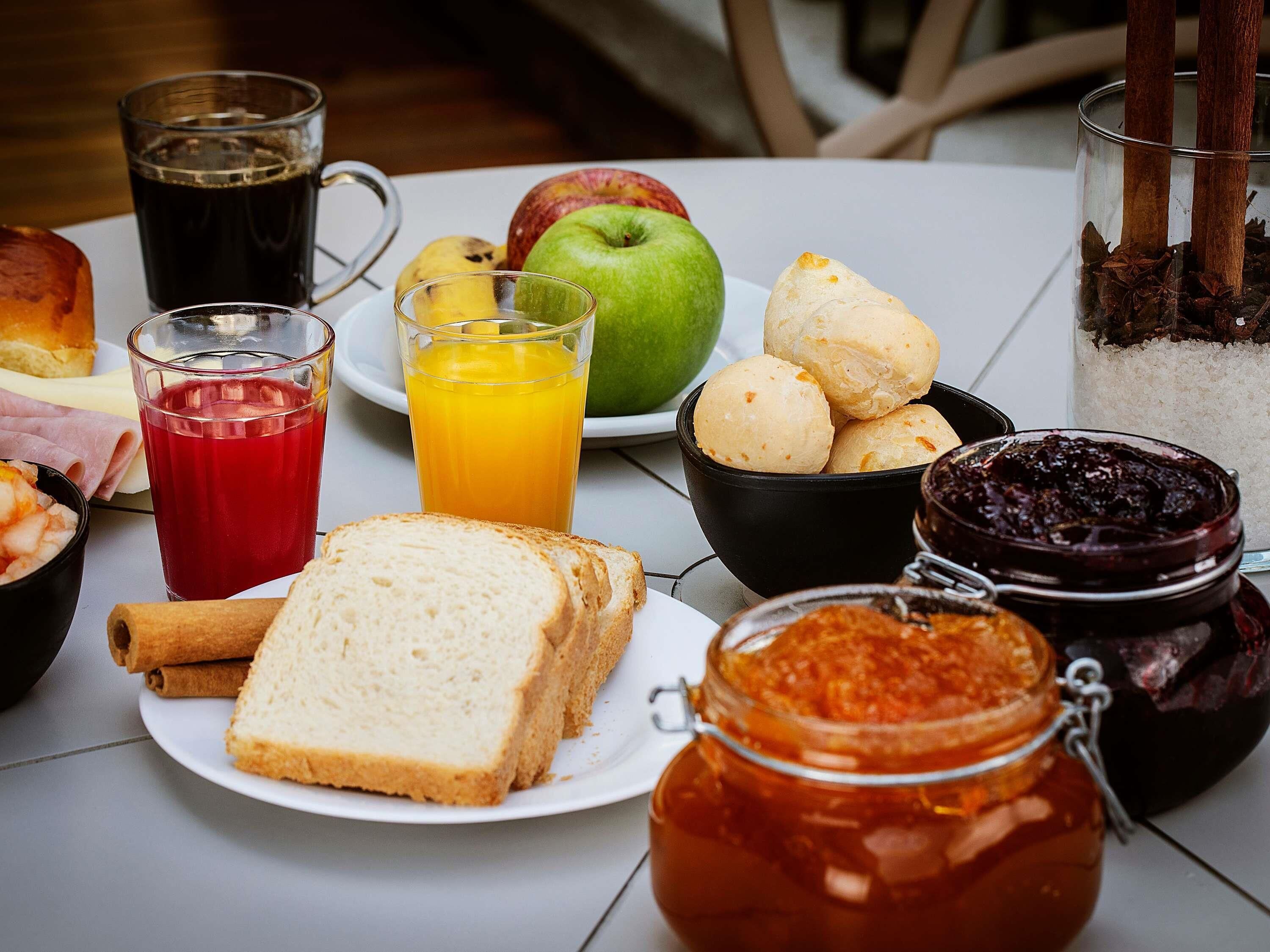 A breakfast table with various food items, including bread, fruits, and condiments.