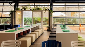 Een modern café met binnenzitplaatsen, grote ramen en potplanten.