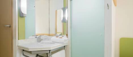 Un baño con lavamanos blanco, espejo y paredes verdes.
