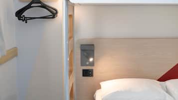 Uma cama beliche com peseira de madeira, mesa de cabeceira e luminária fixada na parede.