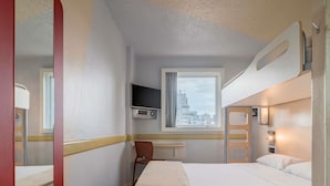 A hotel room with a bed, a TV mounted on the wall, a window with a view of buildings, and a chair. - ibis budget Sao Paulo Paulista (São Paulo)