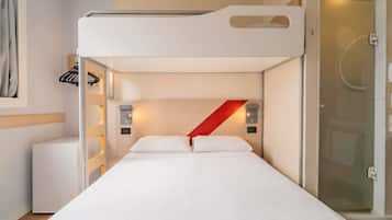 Quarto com beliche, cabeceira branca, parede de destaque vermelha e porta de chuveiro de vidro.