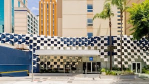A hotel entrance with a checkered facade, a palm tree, and a clear sky. - ibis budget Sao Paulo Paulista (São Paulo)