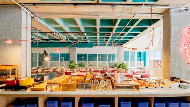 A buffet area with various food items and a seating area with red and white striped benches. - ibis budget Sao Paulo Paulista (São Paulo)