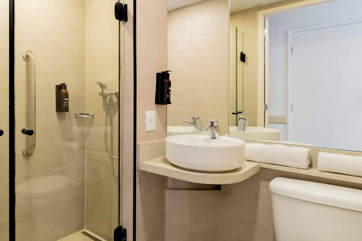 A modern bathroom with a glass-enclosed shower, a white sink, and a toilet.