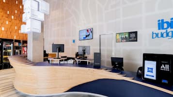 Uma área de recepção moderna com um balcão curvo de madeira, várias estações de computador e uma tela grande exibindo informações.