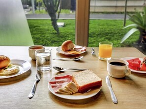 Une table de petit-déjeuner avec des assiettes remplies de nourriture, un verre de jus d’orange et une tasse de café.