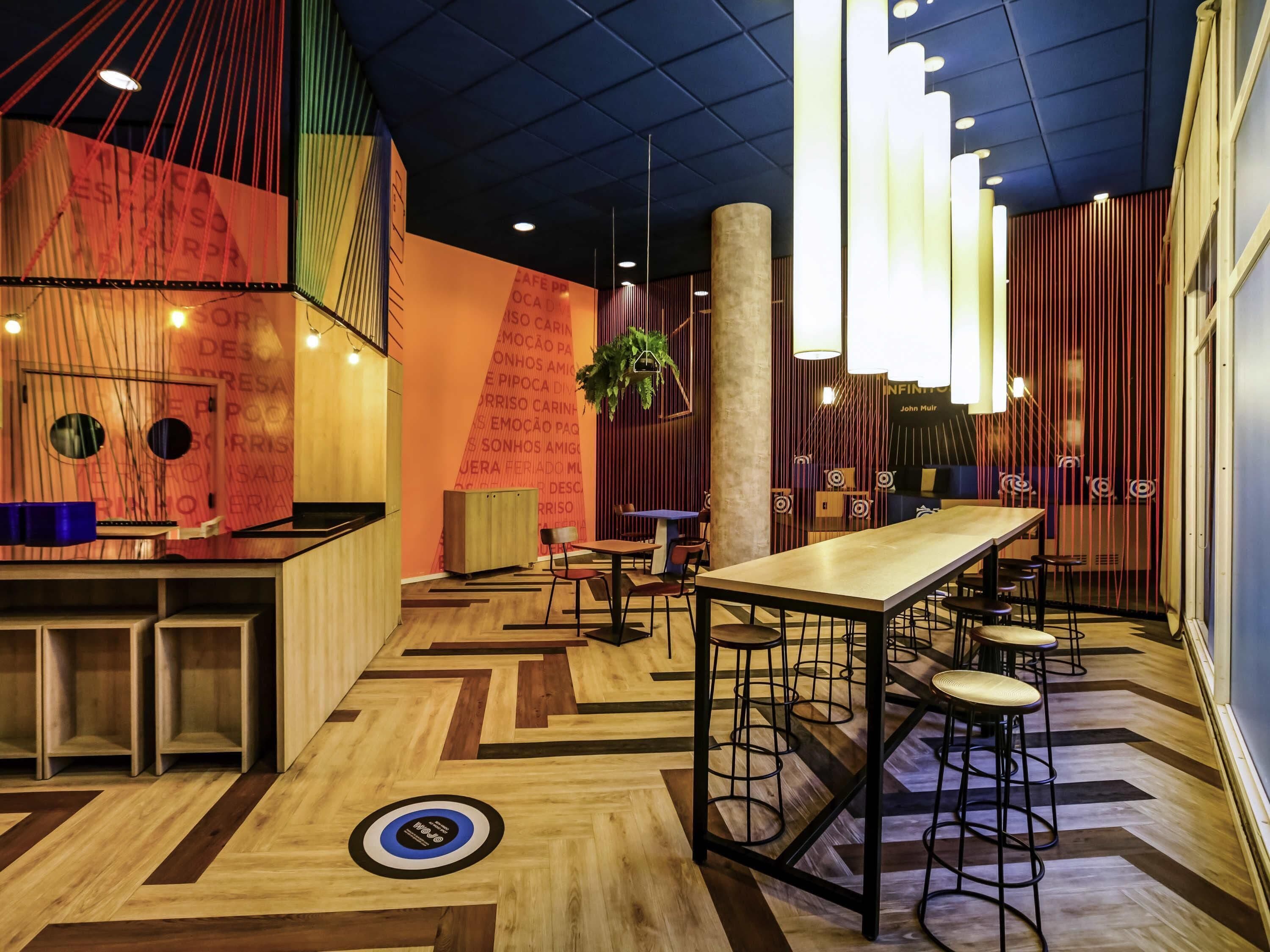 A modern interior with a long communal table, bar area, and seating.
