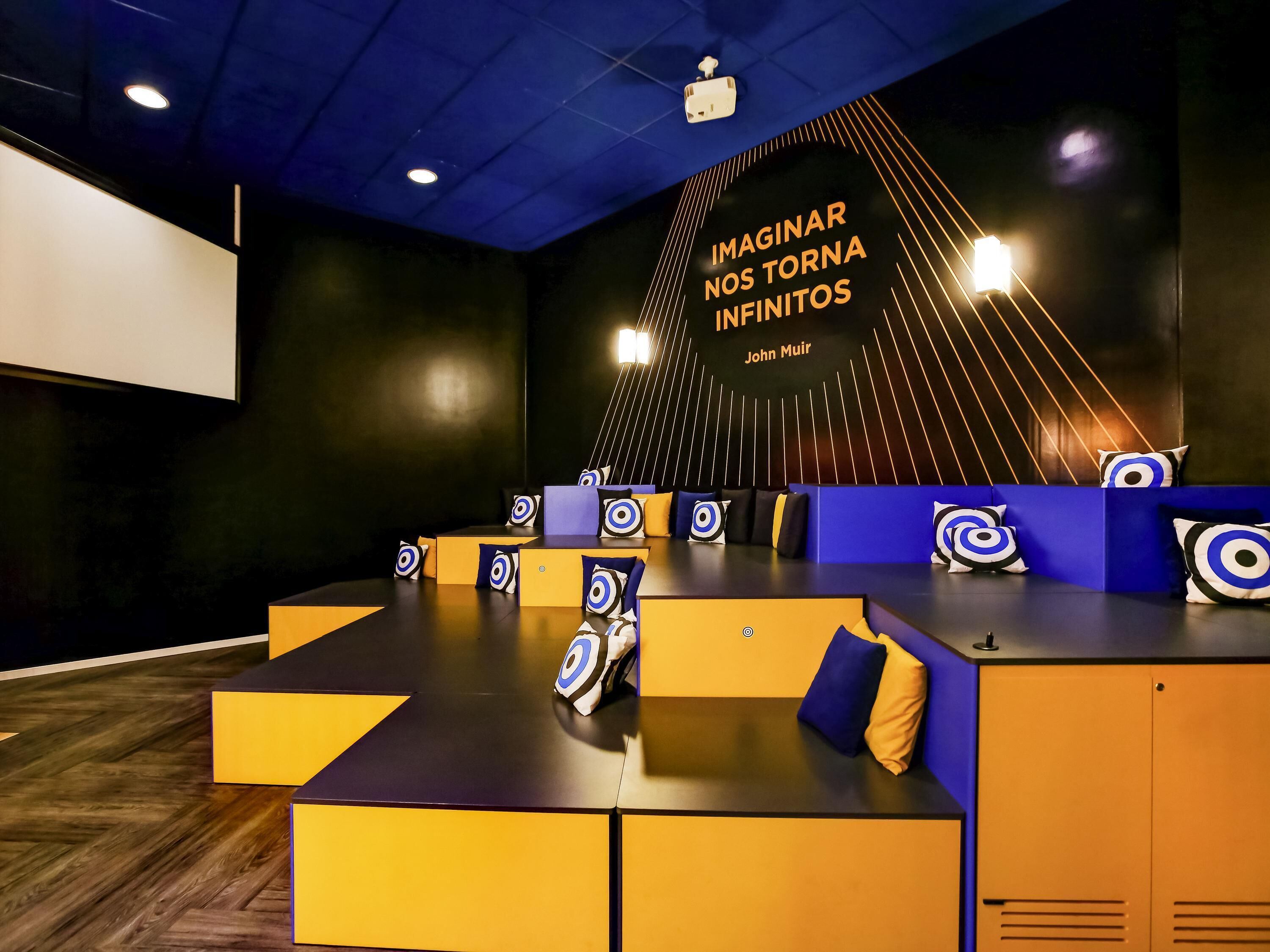 A modern conference room with a stage, seating, and a motivational quote on the wall.