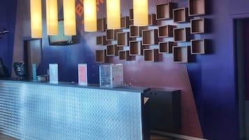 A reception area with a modern design, featuring a textured reception desk, vertical light fixtures, and a patterned wall with geometric shapes.