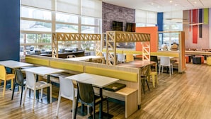 A modern dining area with high tables and booths, large windows, and a brick accent wall. - ibis budget Sao Paulo Morumbi (São Paulo)