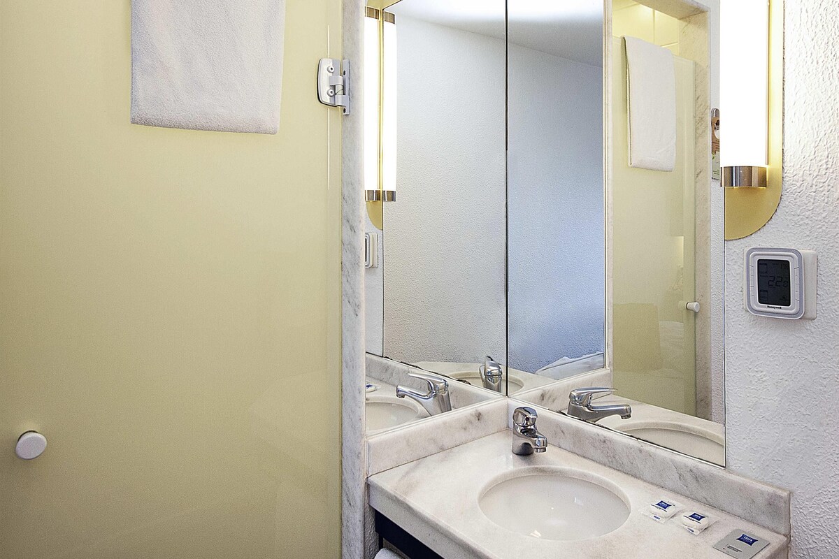 A bathroom with two sinks, a large mirror, and a towel hanging on the wall.
