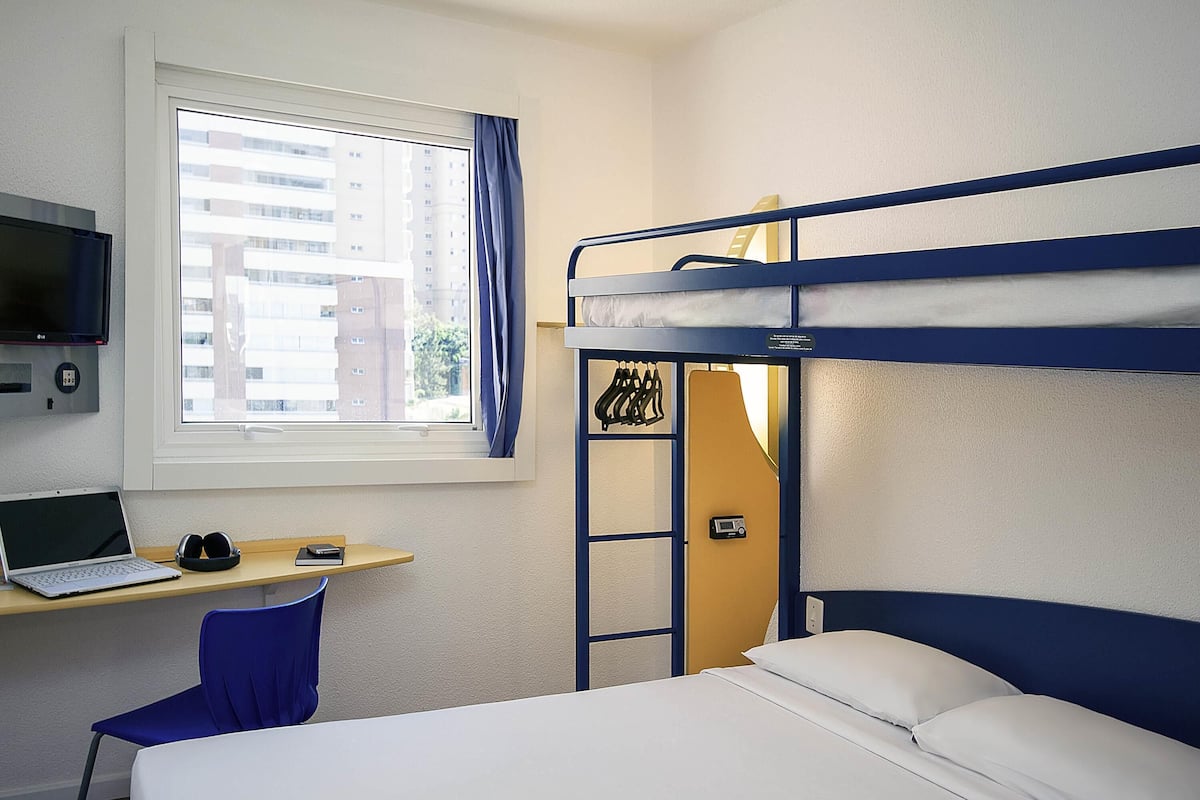 Dormitorio con literas, escritorio, silla y televisor.