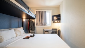 A hotel room with a bed, a desk, a chair, a TV, and a window with curtains. - ibis budget Sao Paulo Morumbi (São Paulo)