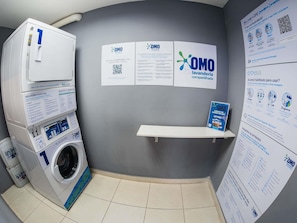 A laundry facility with a washing machine, instructional posters, and a QR code for tutorials. - ibis budget Sao Paulo Morumbi (São Paulo)