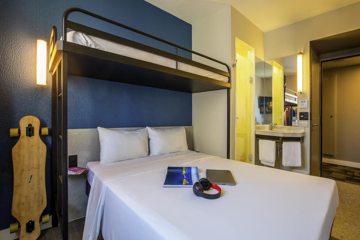 Habitación con literas, un espejo, una laptop y auriculares sobre la cama.