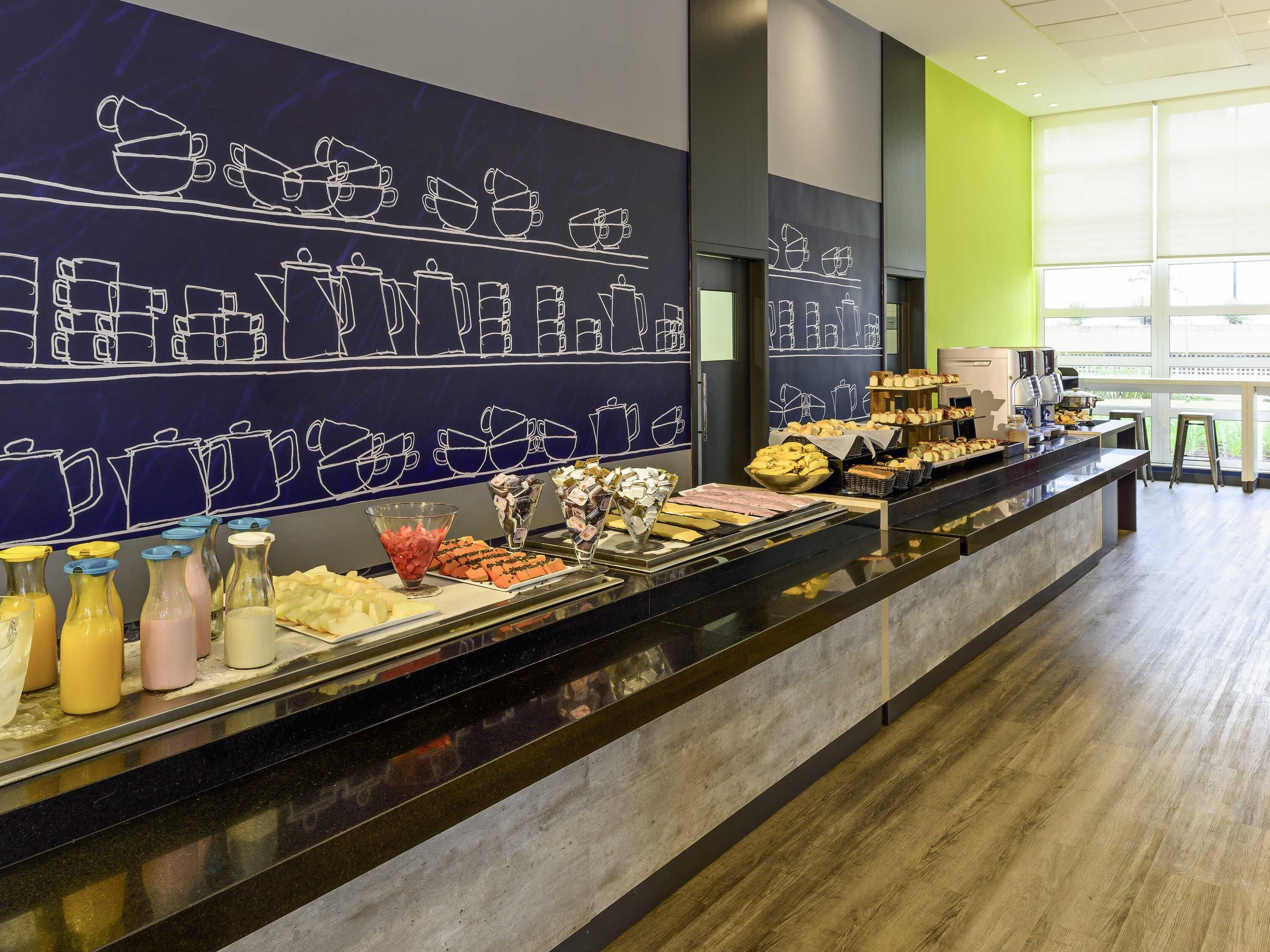 A buffet area with various food items and a wall with coffee cup illustrations.
