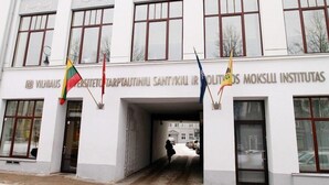 A building with a sign reading "Vihandas Santuiki Ir Politis Moksli Institutas" and multiple flags. - Great Apartment near Town Hall (Vilnius)