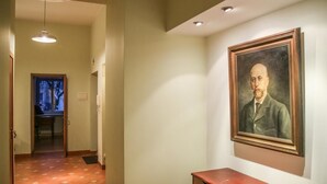 A hallway with a framed portrait on the wall, a wooden bench, and a door leading to another room. - Great Apartment near Town Hall (Vilnius)
