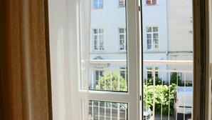 A view through a window with a white frame, revealing a building with multiple windows and balconies. - Great Apartment near Town Hall (Vilnius)