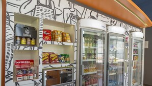 Máquina de vendas com snacks e bebidas, visor de preços baixos e um refrigerador com bebidas.