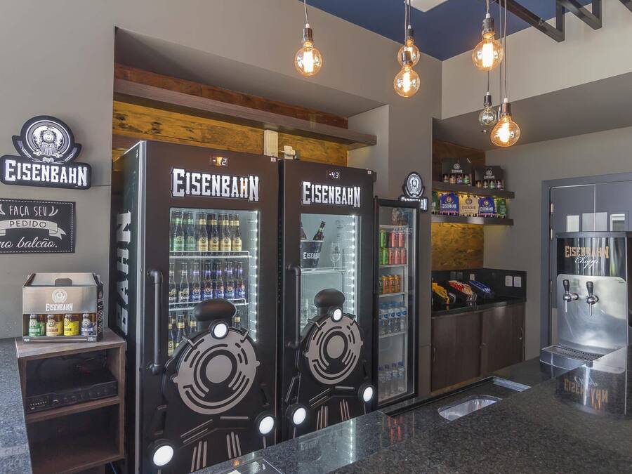 Zona de bar con varias neveras de marca Eisenaahn, una selección de bebidas y un mostrador con caja registradora.