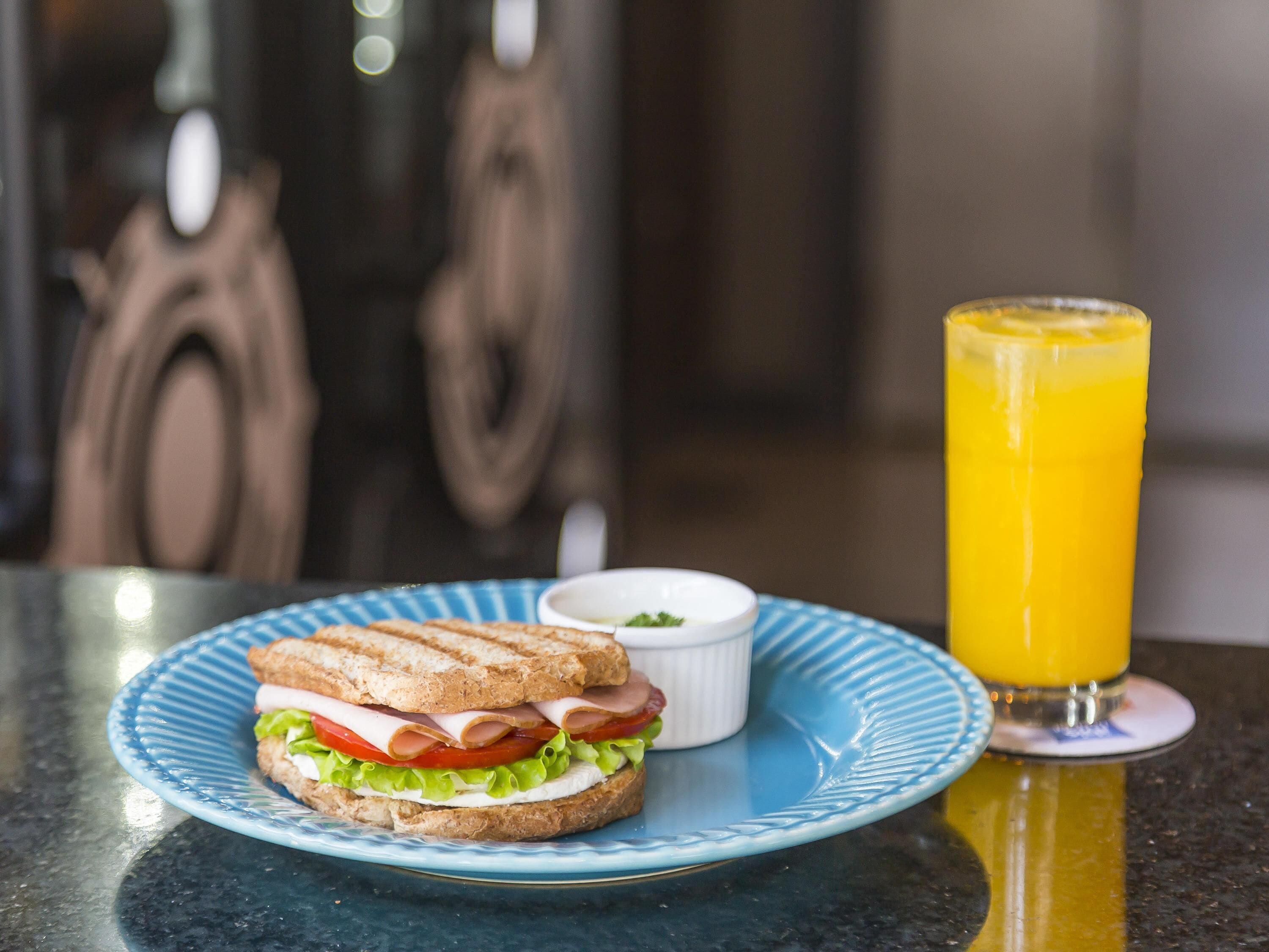A sandwich on a plate with a glass of orange juice.