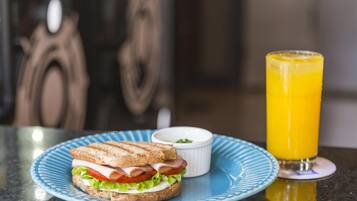 A sandwich on a plate with a glass of orange juice.