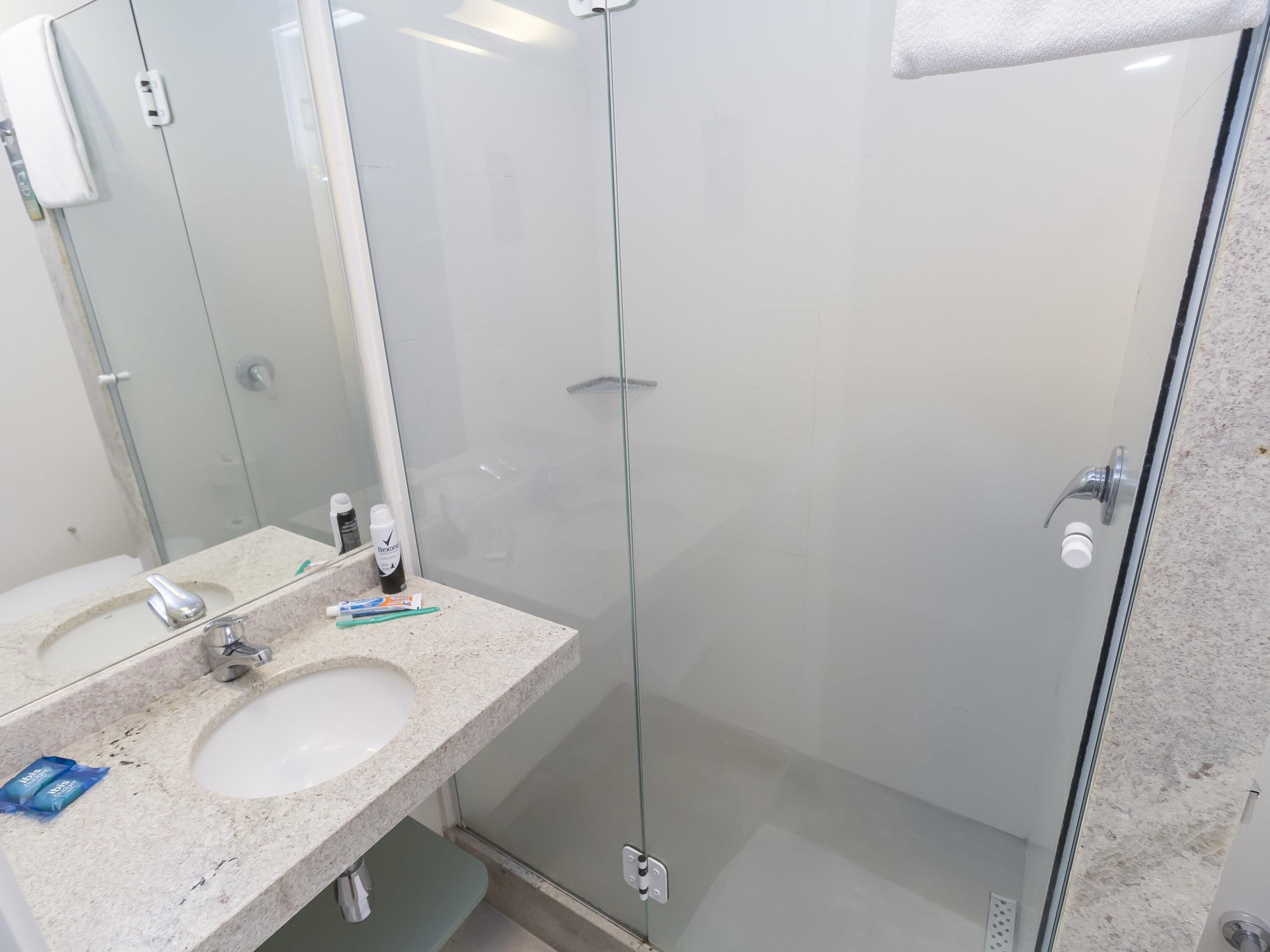 Un baño con cabina de ducha de vidrio, un lavamanos y un espejo.