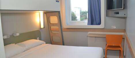 Un letto a castello con una scrivania e una sedia, una televisione e una finestra con tende.