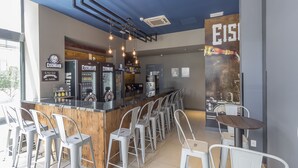 Uma área de bar moderna com balcão, banquetas e luminárias pendentes.