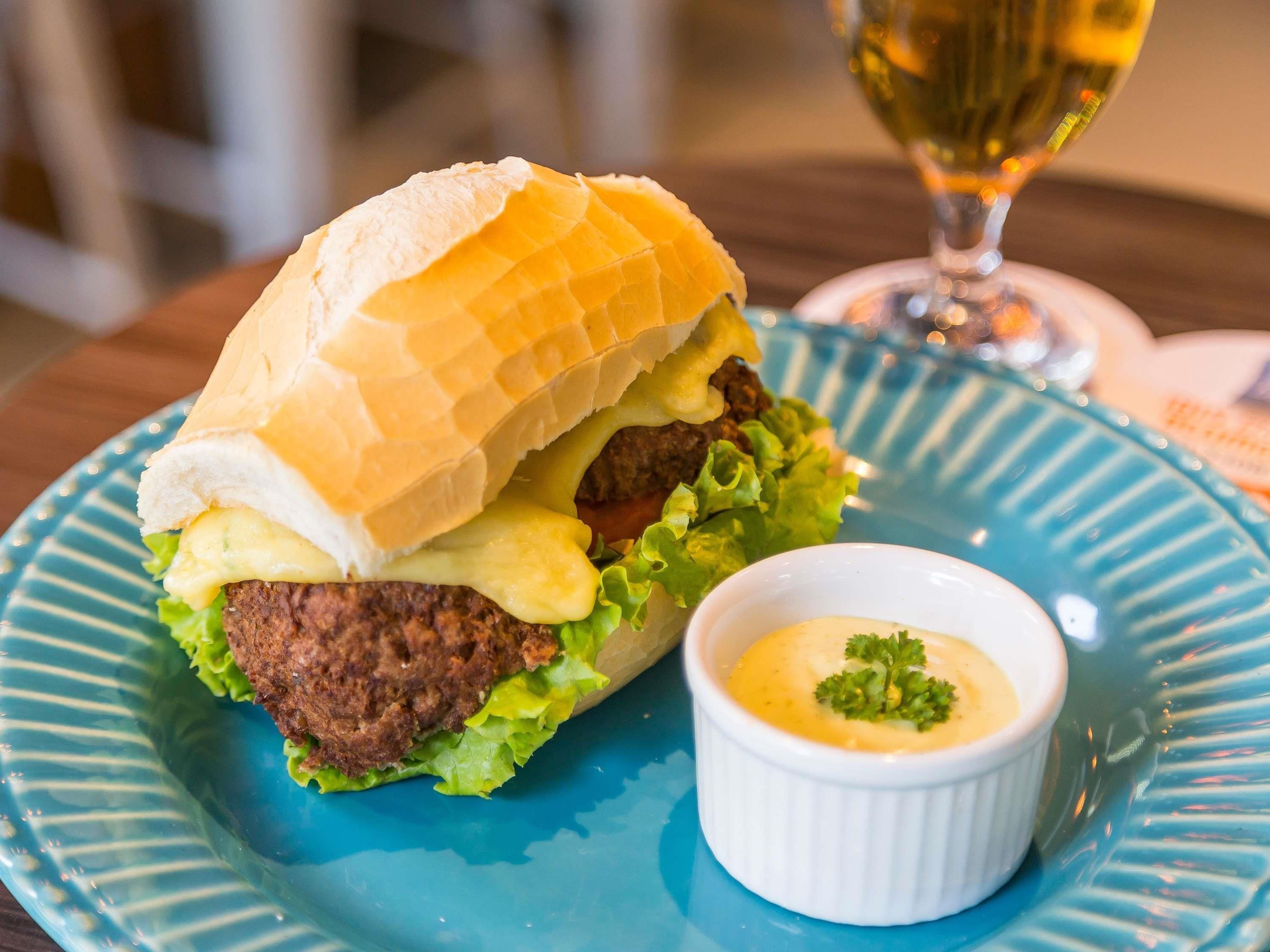 Un sándwich con pan, lechuga y salsa sobre un plato azul.