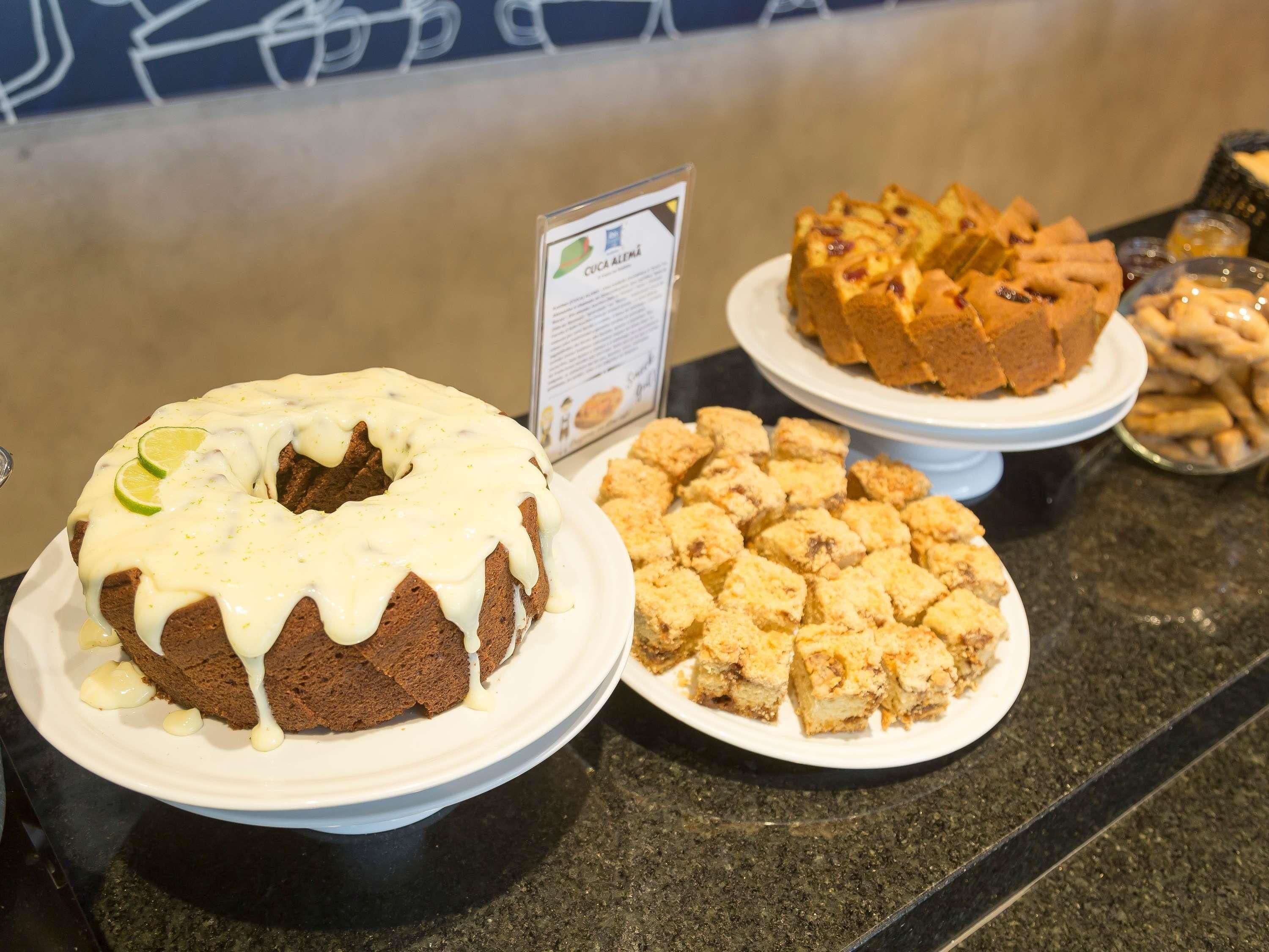 Un bufé con un pastel bundt, un pastel de frutas y una bandeja de postre desmenuzado.