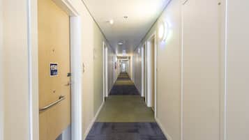 A long, narrow hotel corridor with doors on both sides, a carpeted floor, and a sign indicating the direction to the salon.