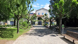 A gravel path leading to a building with a tiled roof and a central archway. -  Les Lavandes (Remuzat)