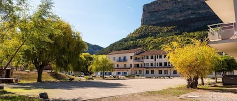 Un patio con edificios, árboles y montañas al fondo.