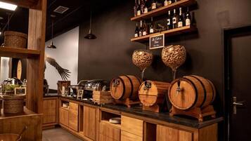 Una zona de bar con armarios de madera, botellas de vino en estantes y barriles de vino.