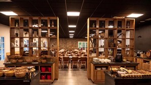 A restaurant with wooden shelves filled with dishes and a central dining area with tables and chairs. -  Les Lavandes (Remuzat)