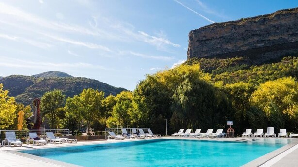 A swimming pool with lounge chairs and a mountainous backdrop. -  Les Lavandes (Remuzat)