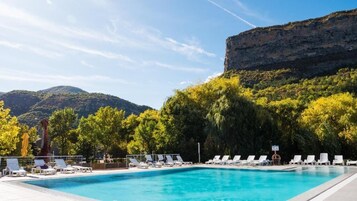 Una piscina al aire libre, sillones reclinables de piscina