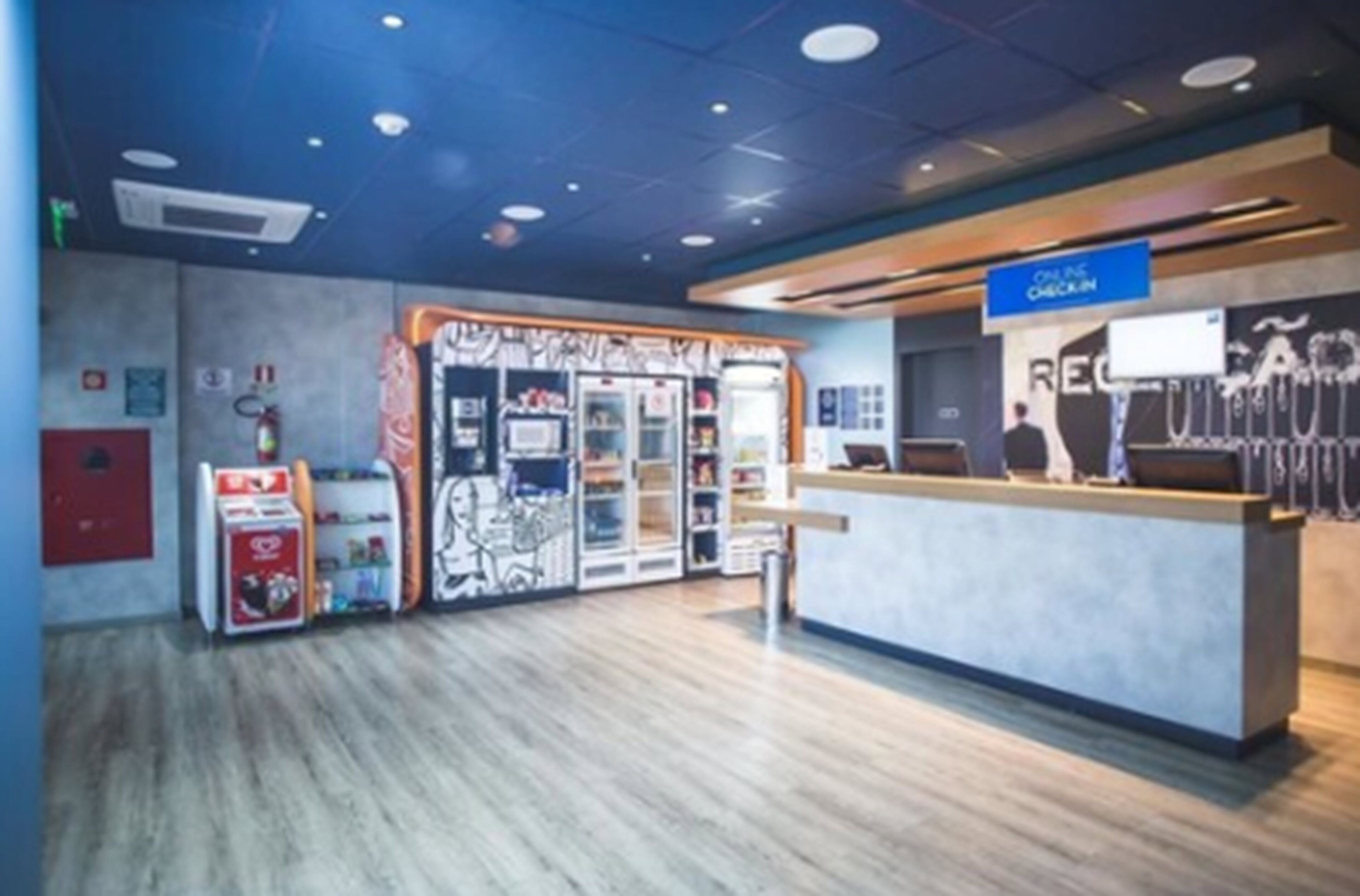 A reception area with a counter, a blue sign above it, and a refrigerator with a colorful design.