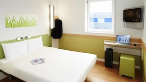 Une chambre d  ’hôtel avec un lit, un bureau avec un ordinateur portable, une télévision et une fenêtre.