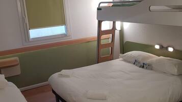 A bunk bed with a green headboard, a bedside table, and a window with blinds.