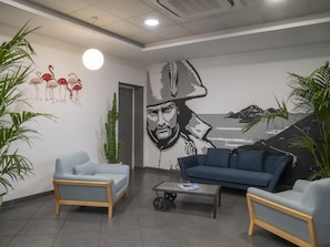 A modern lobby with two sofas, a coffee table, and a mural on the wall.