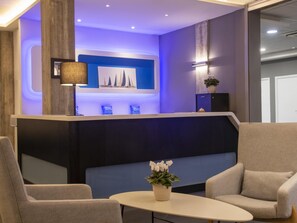 Ett välkomnande område med modern design, som inkluderar en receptionsdisk, en sittgrupp och ett konstverk som hänger på väggen.
