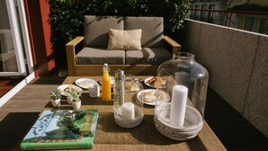 Ein Balkon mit Tisch, gedeckt für ein Frühstück, darunter Teller, Gebäck und ein Buch.